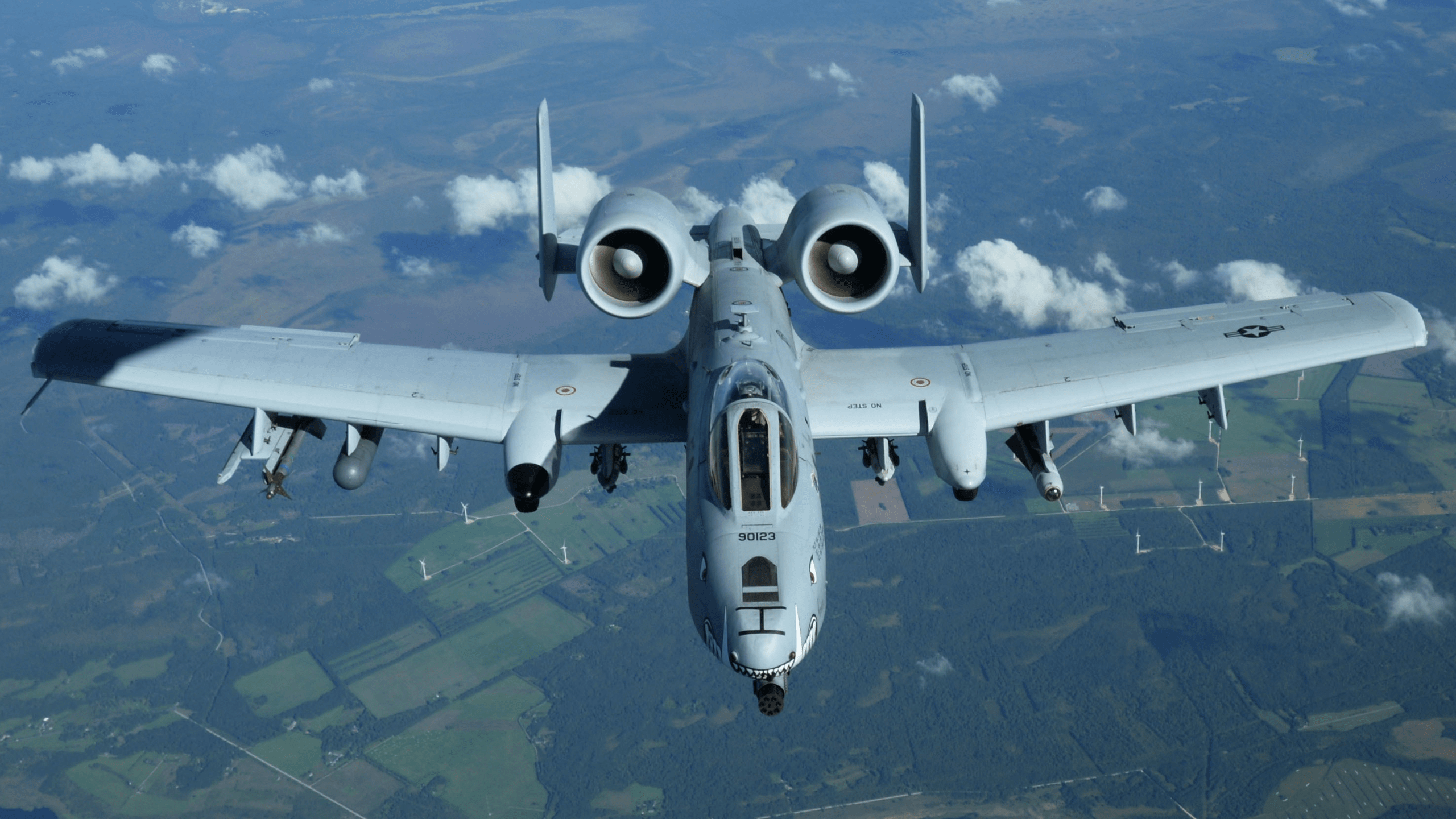 U.S. Air Force A-10 Thunderbolt II aircraft flying head-on above fields and clouds during an aerial flight.